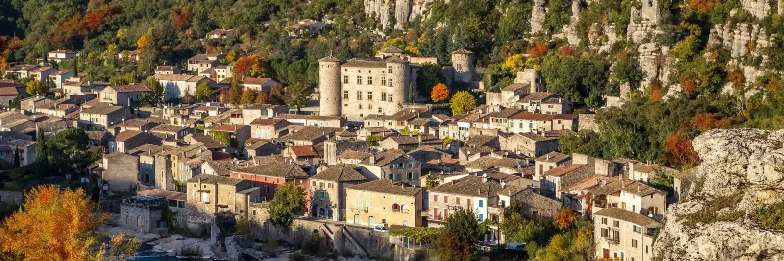 Village médiéval de Vogüé en amphithéâtre avec son château aux quatre tours rondes au bord de la rivière Ardèche