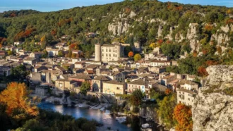 Village médiéval de Vogüé en amphithéâtre avec son château aux quatre tours rondes au bord de la rivière Ardèche