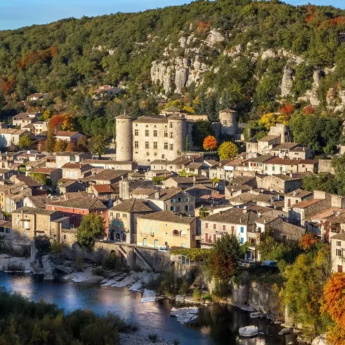 Village médiéval de Vogüé en amphithéâtre avec son château aux quatre tours rondes au bord de la rivière Ardèche