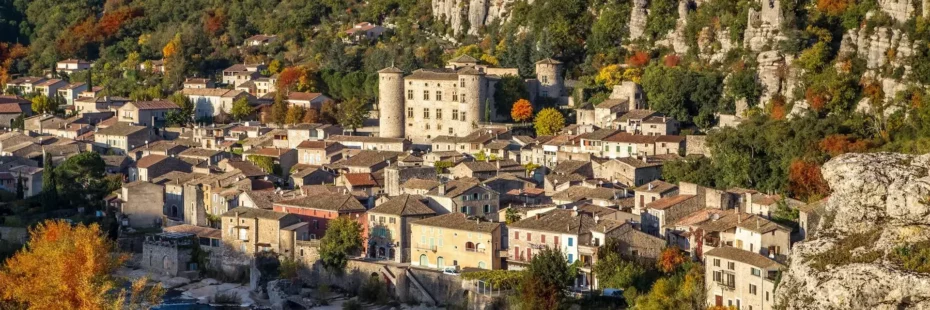 Village médiéval de Vogüé en amphithéâtre avec son château aux quatre tours rondes au bord de la rivière Ardèche