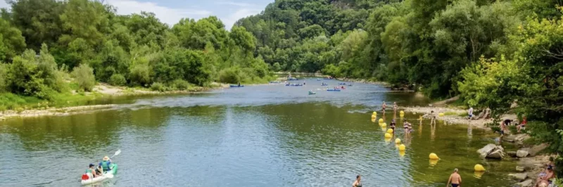 Baignade dans la rivière Ardèche à Saint-Martin-d'Ardèche, eau turquoise et village d'Aiguèze en fond